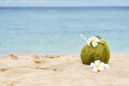 tropical landscape. fresh coconut with a straw and the decor of flowers on a sandy beach