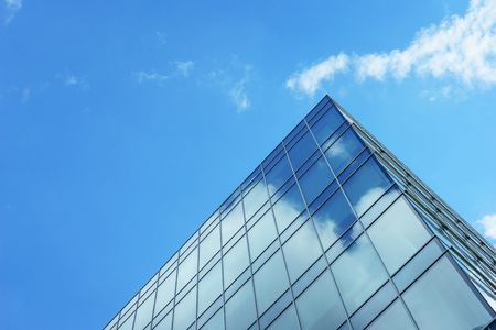 modern office building of glass and concrete. panoramic windows of the building on a background of blue sky and clouds with reflection in glasses.の写真素材