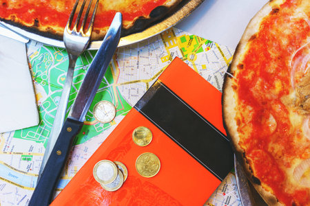 Lunch tourist traditional Italian pizza on a table in a restaurant with a map, some coins and a city...