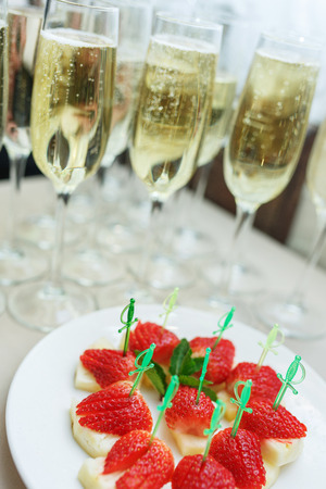 Strawberry fruit as a snack at the event. Snacks on a buffet table - fresh strawberries on pineapple. Catering snack during the event Champagne in glasses with a fruit snack.の写真素材