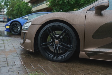Stylish and expensive sports car closeup. Raindrops on a beautiful brown car. The luxurious lifestyle of a rich man - expensive car a parking on a rainy summer day.の写真素材