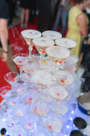 Glasses of champagne set slide on the table in the restaurant during bright holiday. Luxury life festive event for guests. Performance for the participants of the event - champagne and martini glasses.の写真素材