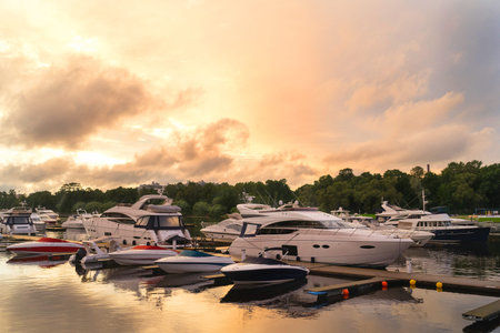 Luxury and high-speed costly yachts and boats at the docks moored to a pier on a summer evening....