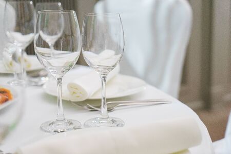 Festively served tables for celebrations and events. Clean utensils, plates and glasses for the drinks prepared for guests. Catering at the wedding and celebrations. Soft focus and beautiful bokeh.の写真素材