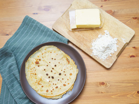 Top view of the ingredients for making traditional thin pancakes and finished pancakes on a plate....