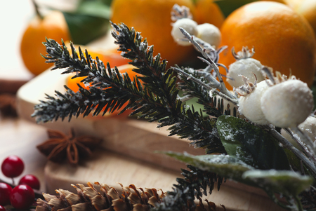 Top view of tangerines with leaves in Christmas decor with Christmas tree, dry orange and berries over old wooden table. Dark rustic styleの写真素材