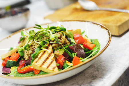 Delicious vegetarian salad with tofu, kinoa and vegetables. A plate of tasty and healthy food - vitamins and health. Soft focus.の写真素材