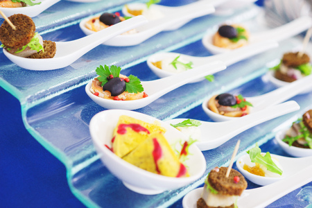 Catering services during events and holidays. Light snacks and canaps, seafood, shrimp, olives on Japanese spoons for miso soup. Soft selective focus and beautiful bokeh.の写真素材