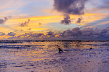 Magic color sunset on the ocean. Silhouettes of surfers who ride the waves at sunset. A romantic...