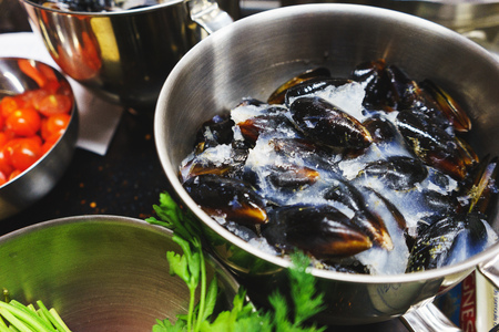Chilled mussels cooked for cooking in the kitchen in a metal saucepan. The process of making pasta with seafood. Top view of a mussel with ice in a metal vessel. Soft selective focus.の写真素材