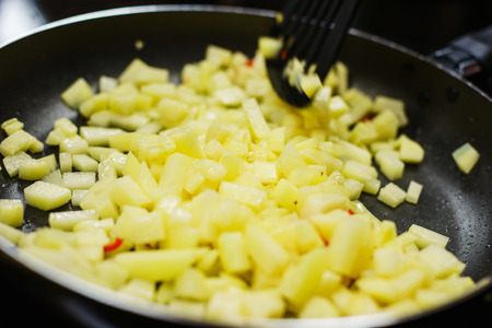 The process of cooking and frying sliced potatoes in a frying pan. Tasty and healthy food, vegetarian food. Vegetables cooked in a frying pan. Soft focus. Closeup.の写真素材