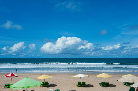 Clean empty tropical beach with sunbeds under the umbrella and a beautiful view of the calm ocean under the blue sky. Travel and leisure on the island, beach vacation. Morning on the beach.の写真素材