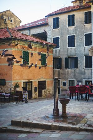July 2017, KOTOR, MONTENEGRO. small square with scenery and cozy outdoor cafes in the old fortified city of Kotor, in Montenegro. Stone ancient houses and architecture of the Middle Ages.のeditorial素材