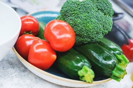 The process of cooking salad from fresh vegetables, tomatoes and cucumbers close-up in a large white bowl. Fresh vegetables in a white plate in the kitchen. Soft focus.の写真素材