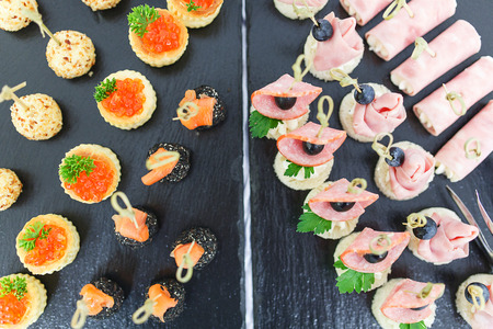 Meals and snacks for guests during the event. Catering. Tapas, canaps, sandwiches, rolls with red fish prepared for the visitors of the event. Close-up and at different angles.の写真素材