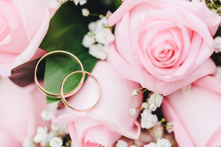 Two elegant gold rings for the wedding of lovers with scenery from fresh roses. Beautiful decoration for the wedding. Festive postcard.の写真素材