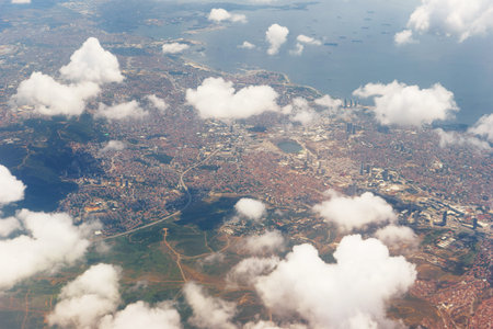 View from the passenger airliner illuminator. Aerial view of the city and clouds from the aircraft...
