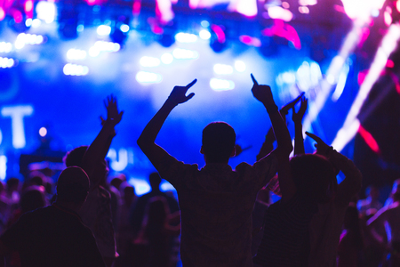 Silhouettes of young people during a bright performance, music festival. Delight from the performance and favorite music. Soft focus, shooting with high sensitivity in difficult conditions.の写真素材