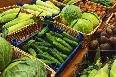Fresh green vegetables in wicker baskets on the counter of a small vegetable market. Ingredients for salads and light snacks. Whole juicy fresh harvest from the farm. Soft focus and beautiful bokeh.の写真素材