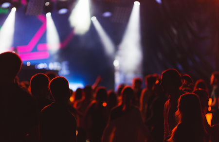 Silhouettes of young people during a bright performance, music festival. Delight from the performance and favorite music. Soft focus, shooting with high sensitivity in difficult conditions.の写真素材