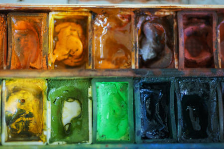 Cuvette with different watercolors. Abstract background concept for school watercolor. Hobbies and education. Artist's tools while working with paint. Stains of paint on special plastic containers.の写真素材