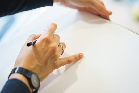 Artist with a pencil close-up while drawing a sketch on clean paper. Preparation and drawing for...