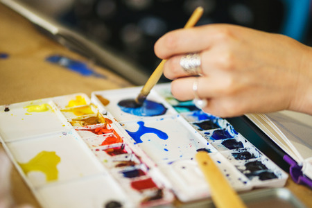 Artist paints with watercolor and kneads paints in a plastic palette. The process of drawing with watercolors.の写真素材