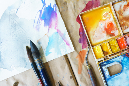 Palette with watercolors in different colors. Various brushes and pencils for drawing prepared by the artist for work.の写真素材