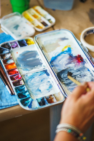 Artist paints with watercolor and kneads paints in a plastic palette. The process of drawing with watercolors.の写真素材