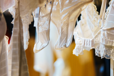 Attractive and seductive lingerie on a hanger in a women's clothing store. Close-up details, lace on a bra and women's lace panties. Sexuality and attractiveness. Sale for the holidays.の写真素材