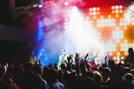 Crowd of young people with their hands up during the performance of your favorite musical group....