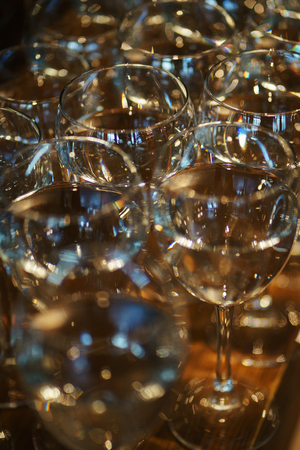 row of transparent wine glasses with drinks on a rack in a bar or restaurant prepared for guests of festive events. catering. alcohol on the counter. soft focus and beautiful bokeh.の写真素材