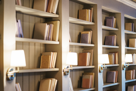 Bookshelves with books. Several different books on the shelves. Interior details in the library. Education and development, reading books and enlightenment. Soft focus and beautiful bokeh.の写真素材