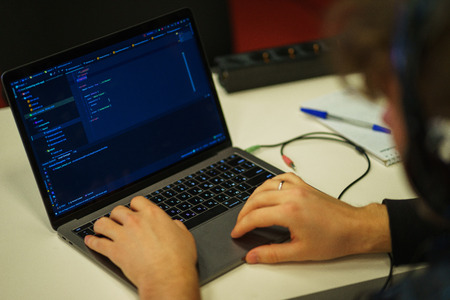 Laptop screen with lines of code. Programmer writes an application in the programming language. Hands of an employee on the keyboard while working on a laptop. Soft focus. Lifestyle.の写真素材