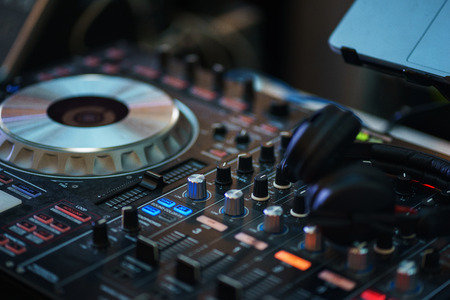 DJ equipment. Player and mixing console with headphones. Night club, music and DJ performance. Nightlife, learning concept. Soft focus and beautiful bokeh.の写真素材