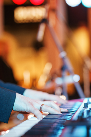 Speech by musicians on stage. Close-up on a musician. Hands and musical instrument closeup. Show in a nightclub, entertainment for adults. Guitar, keys and drum - musical instruments.の写真素材