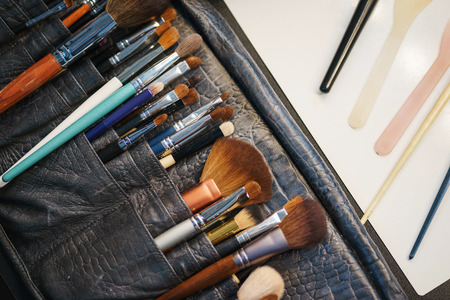 Workplace make-up artist special brushes to create an image and make-up leather case on the table. Modern creative professions. Details and workplace of a professional. Beauty and art. Soft focus.の写真素材