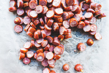 Thinly sliced sausage slices on a black stone board. Traditional meat products, boiled and smoked...