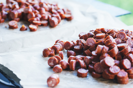 Thinly sliced sausage slices on a black stone board. Traditional meat products, boiled and smoked sausage. Ingredients for cooking. Abstract food background. Soft focus.の写真素材