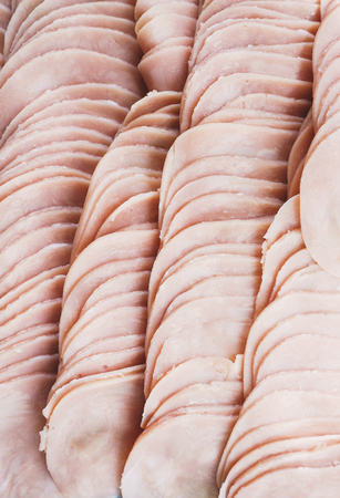 Thinly sliced sausage slices on a black stone board. Traditional meat products, boiled and smoked sausage. Ingredients for cooking. Abstract food background. Soft focus.の写真素材