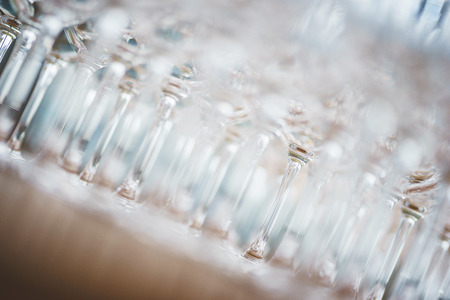 Several rows clear, clean glasses for wine and champagne on counter prepared for drinks. Catering and guest service at the event. Luxury nightlife, holidays and festival. Soft focus beautiful bokeh.の写真素材