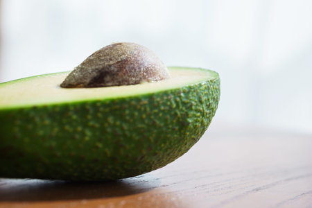 Half fresh avocado, ingredients for cooking on a wooden table in the rays of sun. Vegetarian...