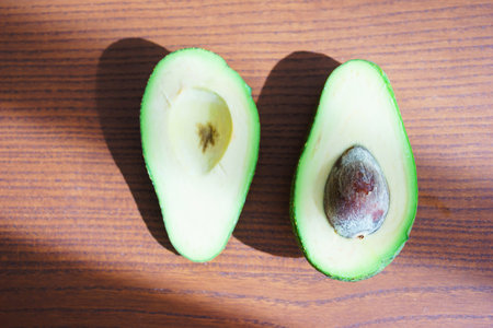 Half fresh avocado, ingredients for cooking on a wooden table in the rays of sun. Vegetarian...