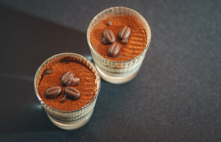 Traditional tiramisu dessert in a glass goblet on the table. Catering and refreshments for guests...