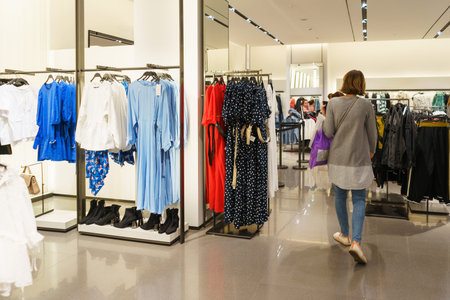 Modern fashion store. Buyers choose clothes. Fashionable men's and women's clothes on hangers in a...
