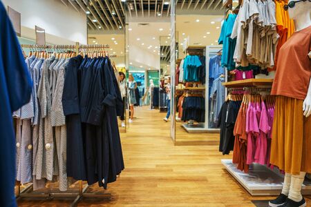 Modern fashion store. Buyers choose clothes. Shirts, hoodies, blouses and half-sweaters, a sweater on a hanger in a clothing store close-up. Sale and shopping in stores. Soft focus.の写真素材