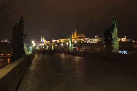 Charles Bridge tourist attraction in Prague, capital of Czech Republic. Long exposure, blurry people at night while walking around the city. Travel old European city. Autumn season. Night photographyの写真素材