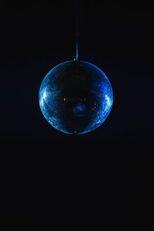 Mirror disco ball under the ceiling in a nightclub. Night life and lighting. Black background and soft focus.の写真素材