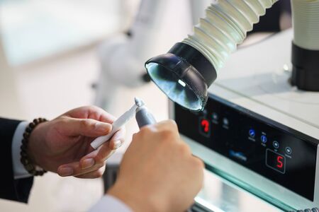 Dental equipment for prosthetics and polishing of teeth, dentures. Hands of a specialist working. Demonstration of the operation polishing machine, hoods and processing the workpiece with a drill.の写真素材