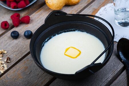 Traditional breakfast. Milk porridge with butter and berries on a wooden table. Classic rustic breakfast, porridge with milk. Healthy tasty food and bright creative serving in the restaurant.の写真素材